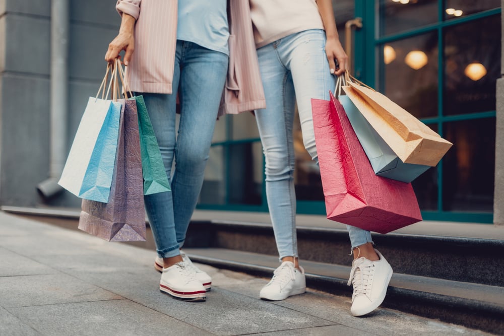 women holding shopping bags in front of boutique