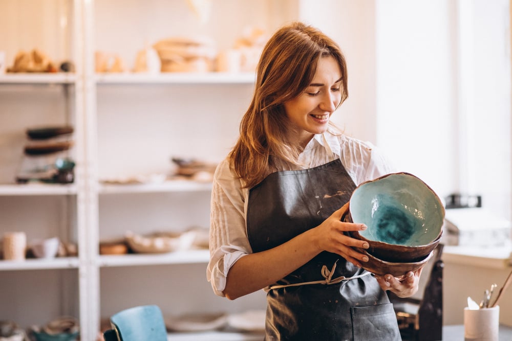 Woman holding handmade pottery bowl in craft shop