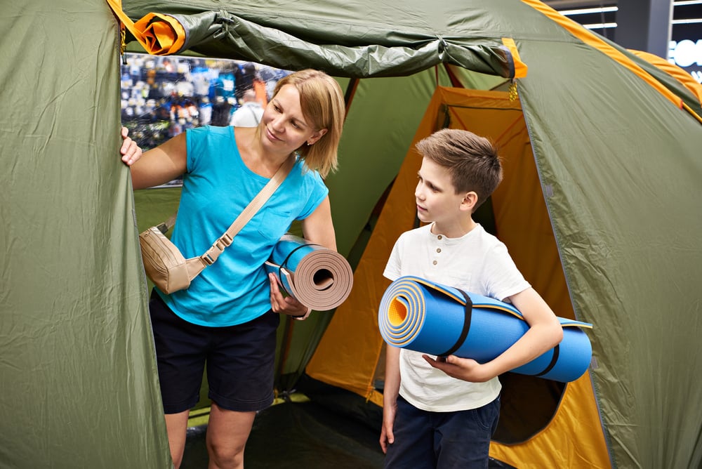 woman and her son looking at a tent holding sleeping pads